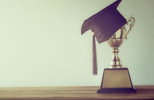 کلاه فارغ التحصیلی با جایزه طلایی قهرمان روی میز چوبی با فضای کپی آماده برای طراحی شما فارغ التحصیلی موفقیت تحصیل مفهوم