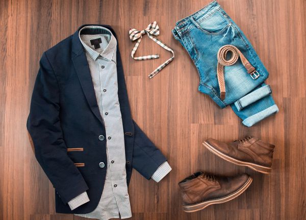 ست لباس راحتی مردانه مانند کت و شلوار آبی با وصله شلوار جین پاپیون چهارخانه کمربند و کفش روی زمینه چوبی قهوه ای نمای بالا