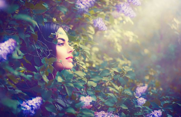 مدل بهار مد پرتره دختر در باغ فانتزی گلهای یاسی زن زیبا تابستانی جذاب با موهای تیره سالم و زیبا با گل های بهاری بنفش روی پس زمینه طبیعت پری