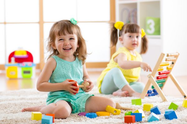 کودکان دختر نوپا در خانه مهدکودک یا مهدکودک اسباب بازی های منطقی برای یادگیری اشکال حساب و رنگ ها بازی می کنند