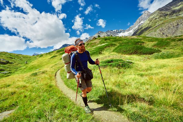 کوهنورد با کوله پشتی در مسیر مراتع سرسبز در کوه های آپلس در نزدیکی کوه ماترهورن حرکت کنید