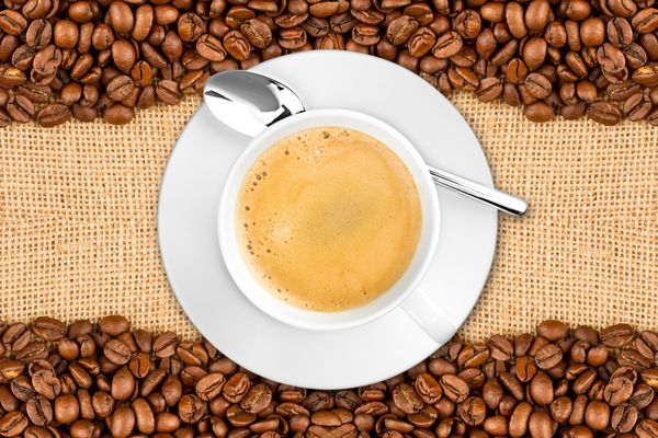 پس‌زمینه فنجان قهوه با دانه‌ها روی جوت کرباسی Kaffeetasse mit Kaffeebohnen auf Jute Sfoff