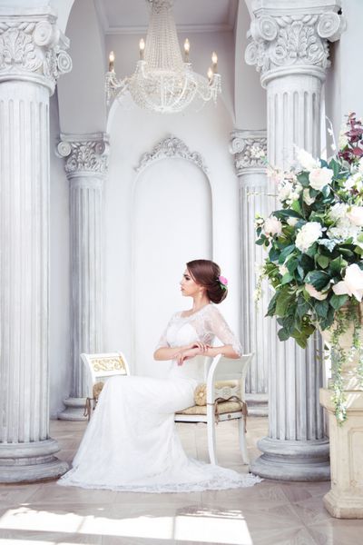 عروس سبزه شیک در سالنی مجلل با ستون نشسته است