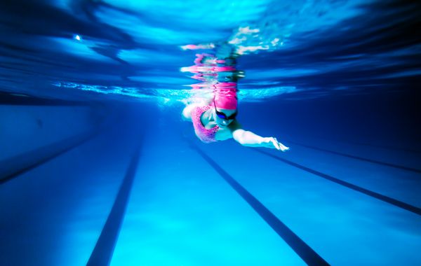 زن شنای آزاد در زیر آب عکس زنی در حال شنا آزاد در استخر المپیک