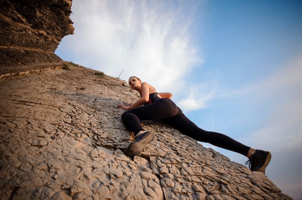 زن جوان در حال بالا رفتن از صخره