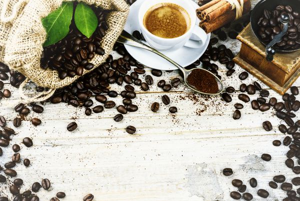 فنجان قهوه سیاه داغ در محیط رترو با آسیاب چوبی قدیمی gr