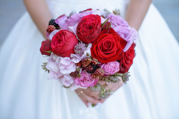 عروس زیبا دسته گل رنگارنگ عروسی را در دست گرفته است زیبایی گل های رنگی دسته گلچه از نمای نزدیک لوازم عروس دکوراسیون زنانه برای دختر جزئیات برای ازدواج و برای زوج متاهل