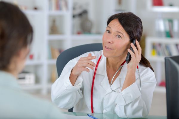 دکتر با بیمار و صحبت کردن با تلفن
