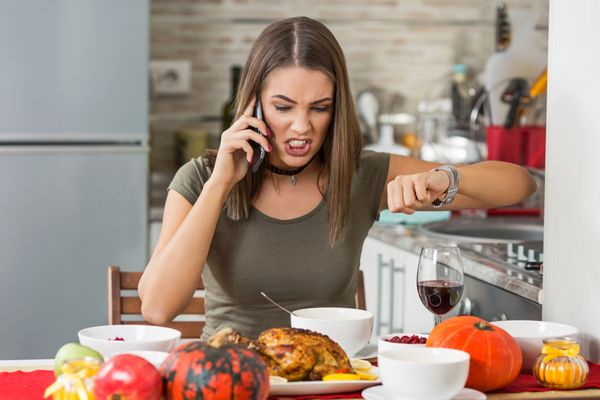 زن جوان عصبانی پشت میز ناهار خوری نشسته و پشت تلفن روی دوست پسرش فریاد می زند که دوباره برای شام دیر کرده است
