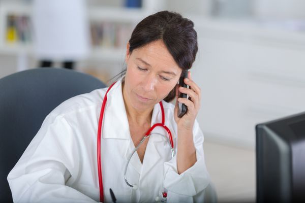 دکتر زن خوش تیپ با تلفن در مطبش