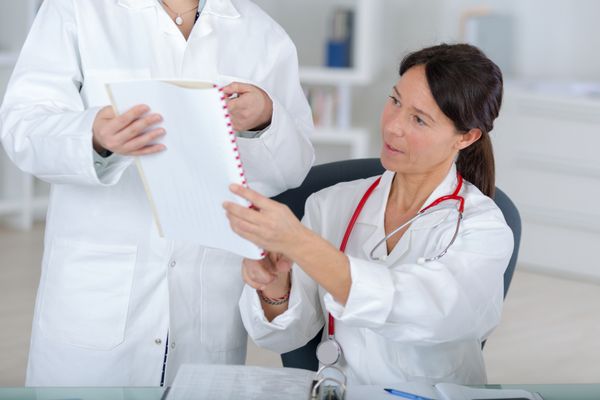 دکتر زن جذاب که با همکار خود در مطب پزشکان مشورت می کند