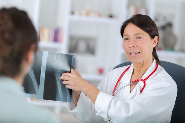 دندانپزشک زن در حال نشان دادن اشعه ایکس به بیمار