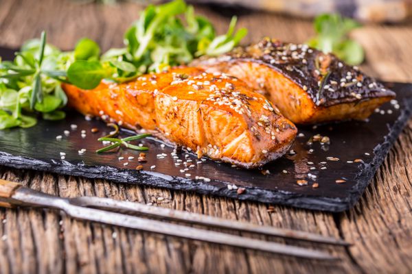فیله ماهی قزل آلا تزیین گیاه سالمون کبابی دانه کنجد روی تابه قدیمی یا تخته تخته سنگ سیاه ماهی بریان شده روی میز چوبی قدیمی شات استودیو