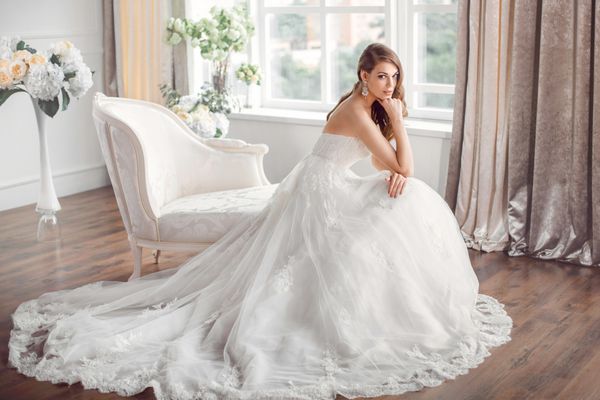 عروس با لباسی زیبا روی مبل داخل خانه نشسته است