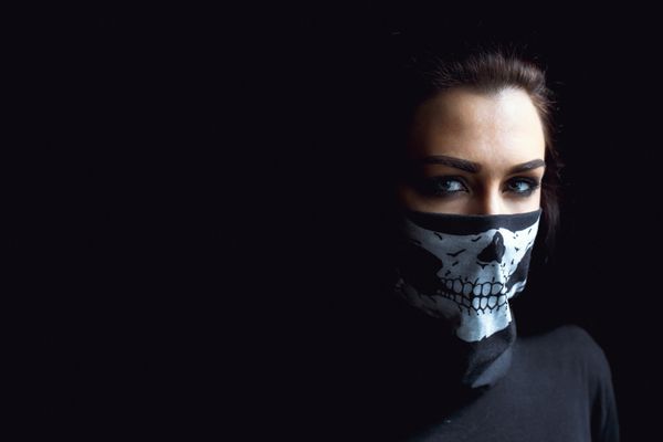 زن تهاجمی زیبا در پس زمینه تاریک زنی با روسری جمجمه سیاه روی صورتش نمای نزدیک استودیو