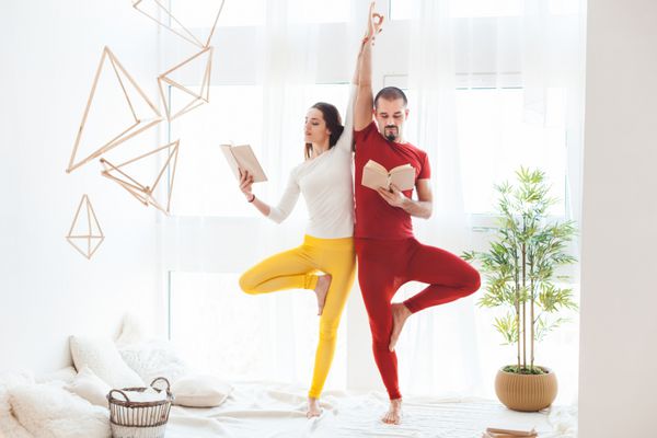 مرد و زن در حال انجام تمرینات یوگا در خانه