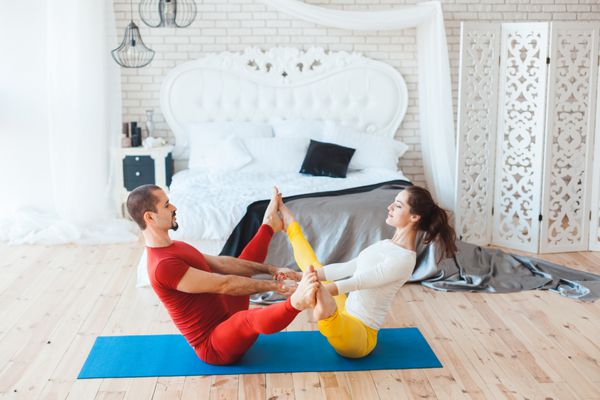 زن و مرد هنگام ورزش صبحگاهی در خانه عضلات خود را کشش می دهند