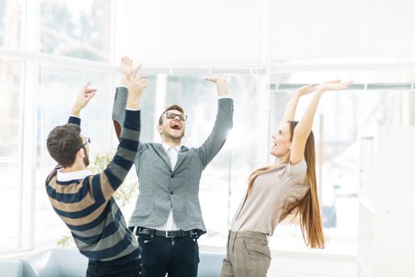 مفهوم پیروزی - تیم تجاری شادی آور که در یک دایره ایستاده اند دستان خود را به نشانه موفقیت خوشحال می کنند