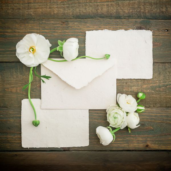 کارت های خوشنویسی کاغذی پاکت نامه و گل های سفید در زمینه چوب تخت خوابیده نمای بالا پس زمینه قدیمی
