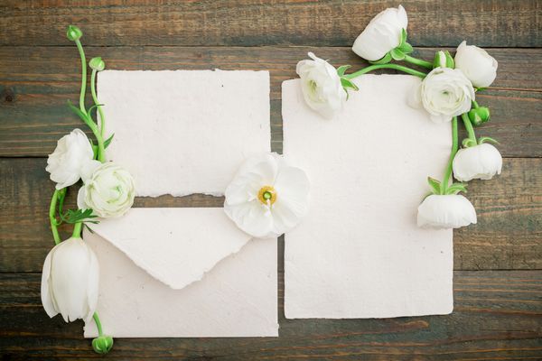 کارت پستال کاغذی پاکت نامه و گل های سفید در زمینه چوب تخت خوابیده نمای بالا پس زمینه قدیمی