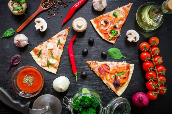 پیتزا ایتالیایی با مواد و سبزیجات روی میز تاریک تخت خوابیده نمای بالا الگوی پیتزا برش خورده