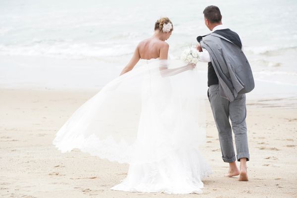 زوج تازه ازدواج کرده شاد در حال قدم زدن در ساحل