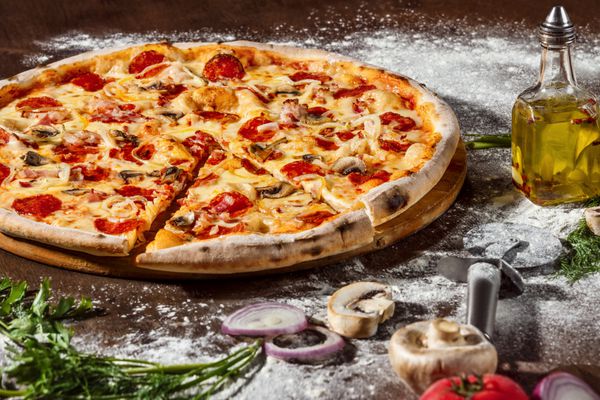 پیتزا ایتالیایی با فلفل پنیر قارچ و سالامی در زمینه میز چوبی روستایی تصویر نزدیک