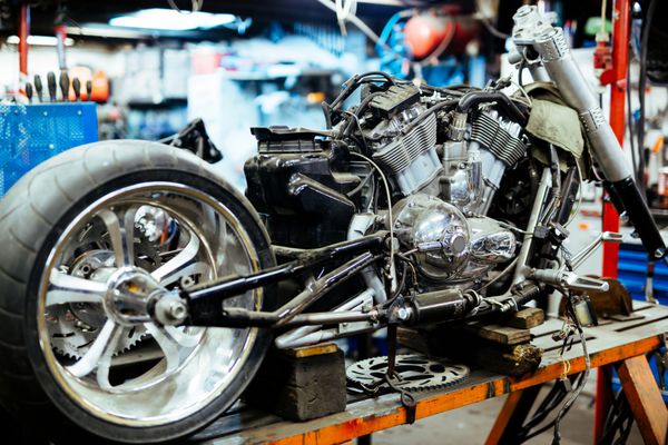 تصویر پس زمینه موتور سیکلت جدا شده بزرگ روی پایه در کارگاه آماده برای تعمیر تنظیم و سفارشی سازی کارها