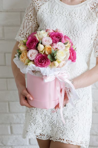 دختر ناشناخته با هدیه دسته گل رز لوکس بوکس گل های رنگارنگ در جعبه صورتی به شکل استوانه هدیه ای زیبا و احساسی برای 8 مارس روز ولنتاین