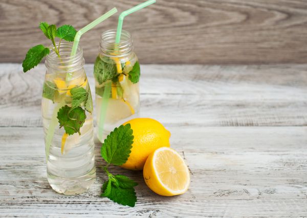 لیموناد تازه نوشیدنی سرد در یک بطری شیشه ای نمای نزدیک روی پس زمینه چوبی