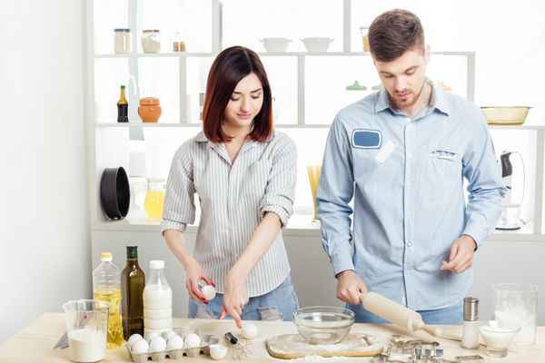 زوج خوشحال عاشق پختن خمیر در آشپزخانه