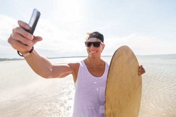 مرد جوان شاد با اسکیم برد در ساحل تابستانی