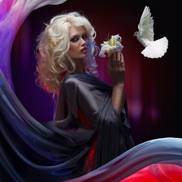 پرواز کبوتر سفید نزدیک به دختر بلوند جذاب که زنبق سفید را در دست دارد