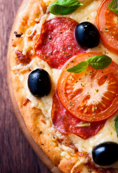 نمای نزدیک از پیتزا با سالامی و گوجه فرنگی