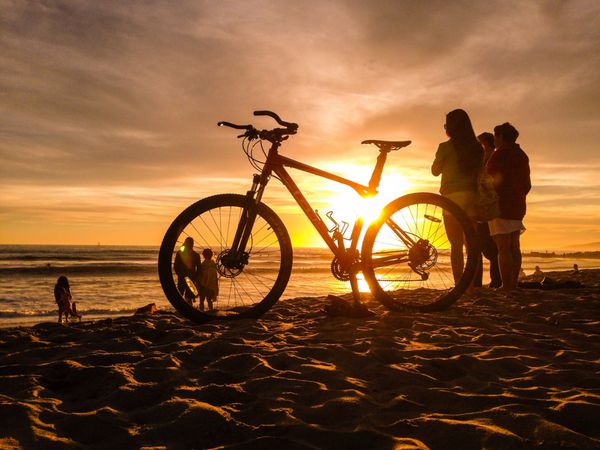 خورشید غروب خورشید از طریق دوچرخه در ساحل ونیز در لس آنجلس می تابد
