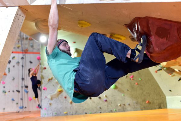 Junger sportlicher Mann klettert Bouldert indoor in einer Kletterhalle صعود در فضای داخلی