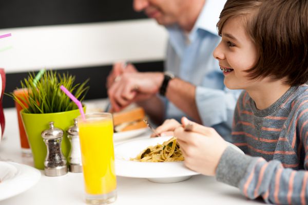 پسر شاد با پدرش از صبحانه در رستوران لذت می برد