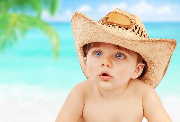 پرتره نزدیک از پسر بچه زیبا پوشیدن کلاه کابوی بزرگ در ساحل تعطیلات تابستان شاد لذت داشتن در خارج از منزل