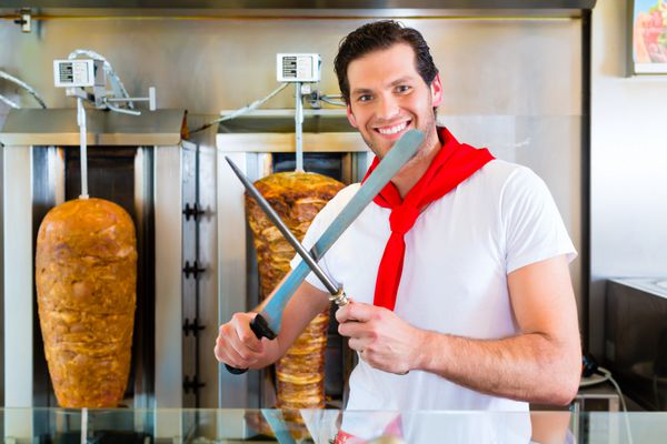 دونر کباب فروشنده دوستانه در یک غذای سریع سوپرمارکت ترکی برش گوشت با چاقوی تیز در مقابل سرب