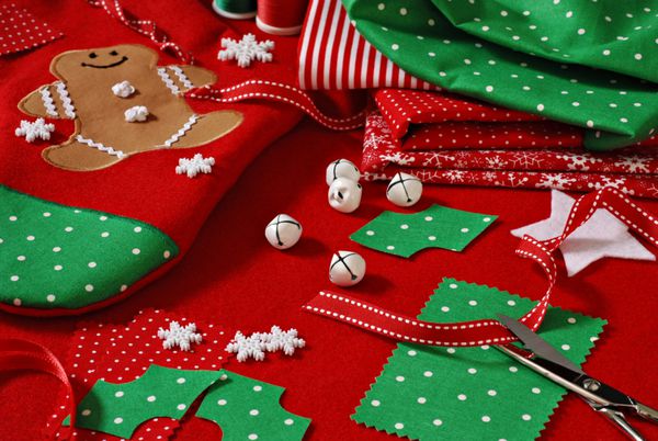 زندگی کریسمس خیاطی همچنان شامل لوازم پارچه و صنایع دستی برای ایجاد دکوراسیون و تزئینات جشن می باشد جوراب بافی دست ساز با مرد شیرینی زنجفیلی پخته شده در پس زمینه