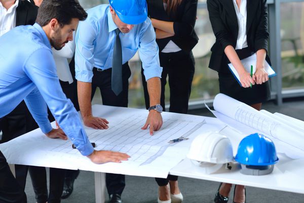 گروه های کسب و کار در جلسه و ارائه در دفتر مدرن روشن با معمار مهندس ساختمان و کارگر به دنبال مدل ساخت و ساز و طرح planbleprint طرح