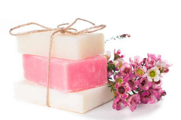 صابون سفید و صورتی دست ساز و شکوفه های گیلاس صورتی بر روی زمینه سفید جدا شده است هدایا و سوغاتی دست ساز