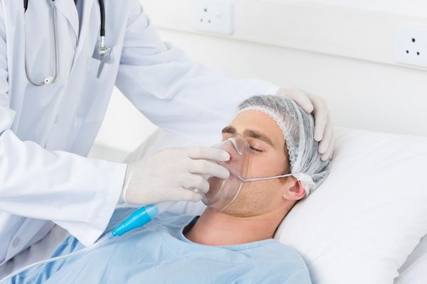 متوسط ​​مردان دکتر تنظیم ماسک اکسیژن در بیمار در بخش بیمارستان