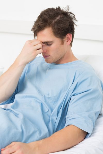 بیمار مبتلا به ضعیف مبتلا به سردرد است که در بستر بیمارستان استراحت می کند