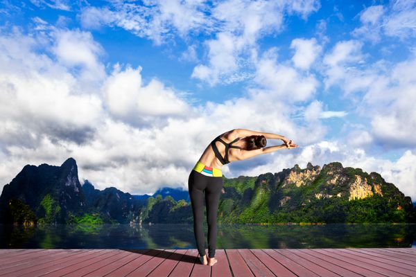 زن جوان تمرین یوگا در دریاچه کوهستان