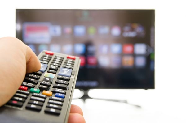 تلویزیون هوشمند و دست با فشار دادن کنترل از راه دور