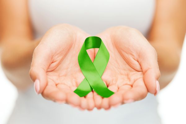 مفهوم مراقبت های بهداشتی و پزشکی دستان زنانی که روبان آگاهی پیوند عضو بدن سبز دارند