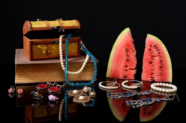 جعبه با طلا و جواهر کتاب و هندوانه روی میز