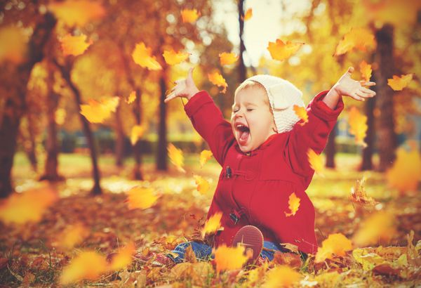 کودک کوچک دختر بچه خنده و در پاییز در طبیعت راه رفتن در خارج از منزل