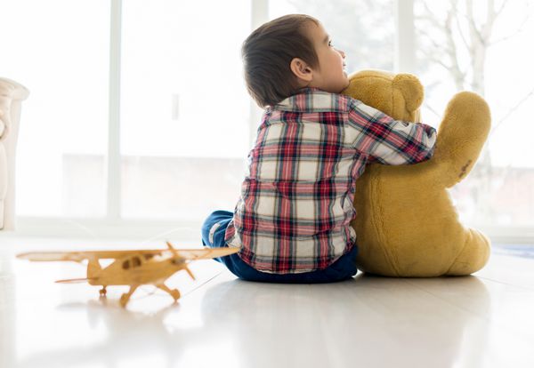 پرتره کودک نشسته در اتاق نشیمن با تدی خرس